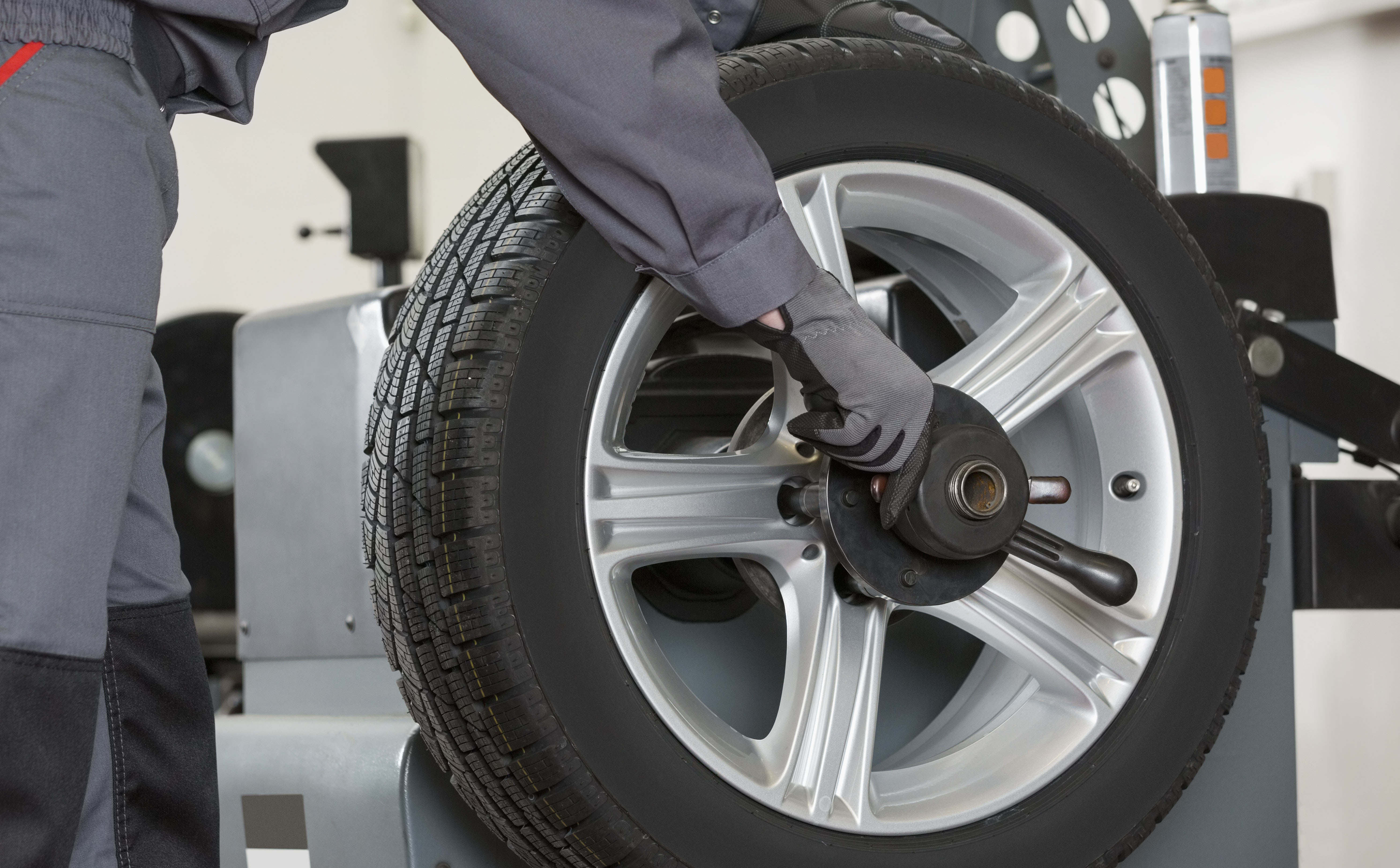 Середня частина чоловічого механіка ремонтує колесо автомобіля в ремонтній майстерні